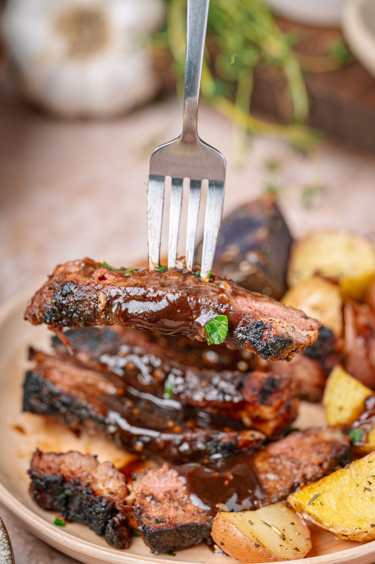Fork lifting sliced steak coated in dark stout pan sauce. Dark stout pan sauce spooned over sliced steak with a charred cocoa spice crust.
