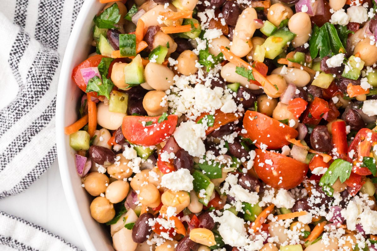High protein dense bean salad with chickpeas, black beans, cannellini beans, feta cheese, tomatoes, cucumber, and parsley