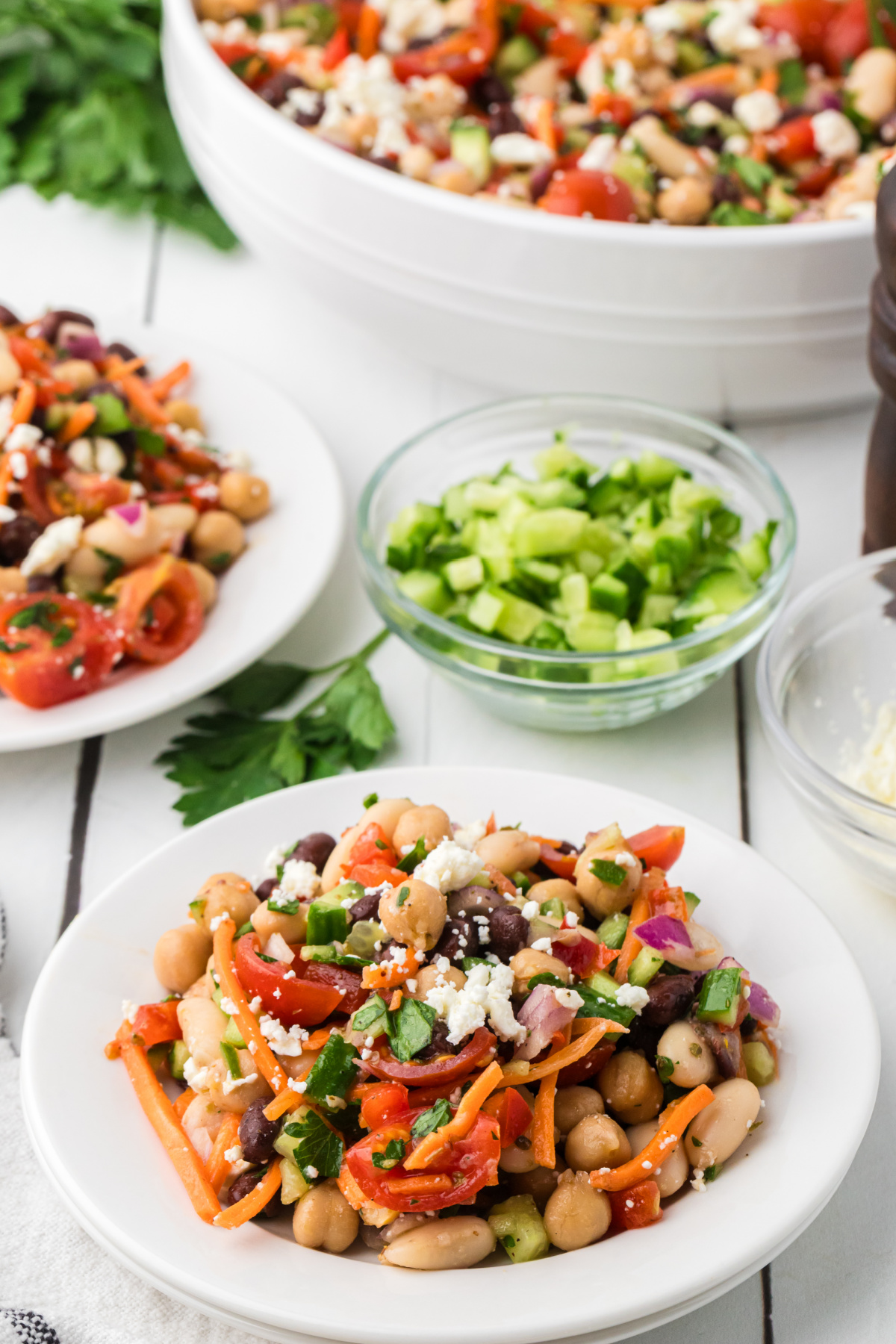 Make-ahead bean salad lunch with chickpeas, black beans, cannellini beans, feta cheese, cucumber, tomatoes, and parsley