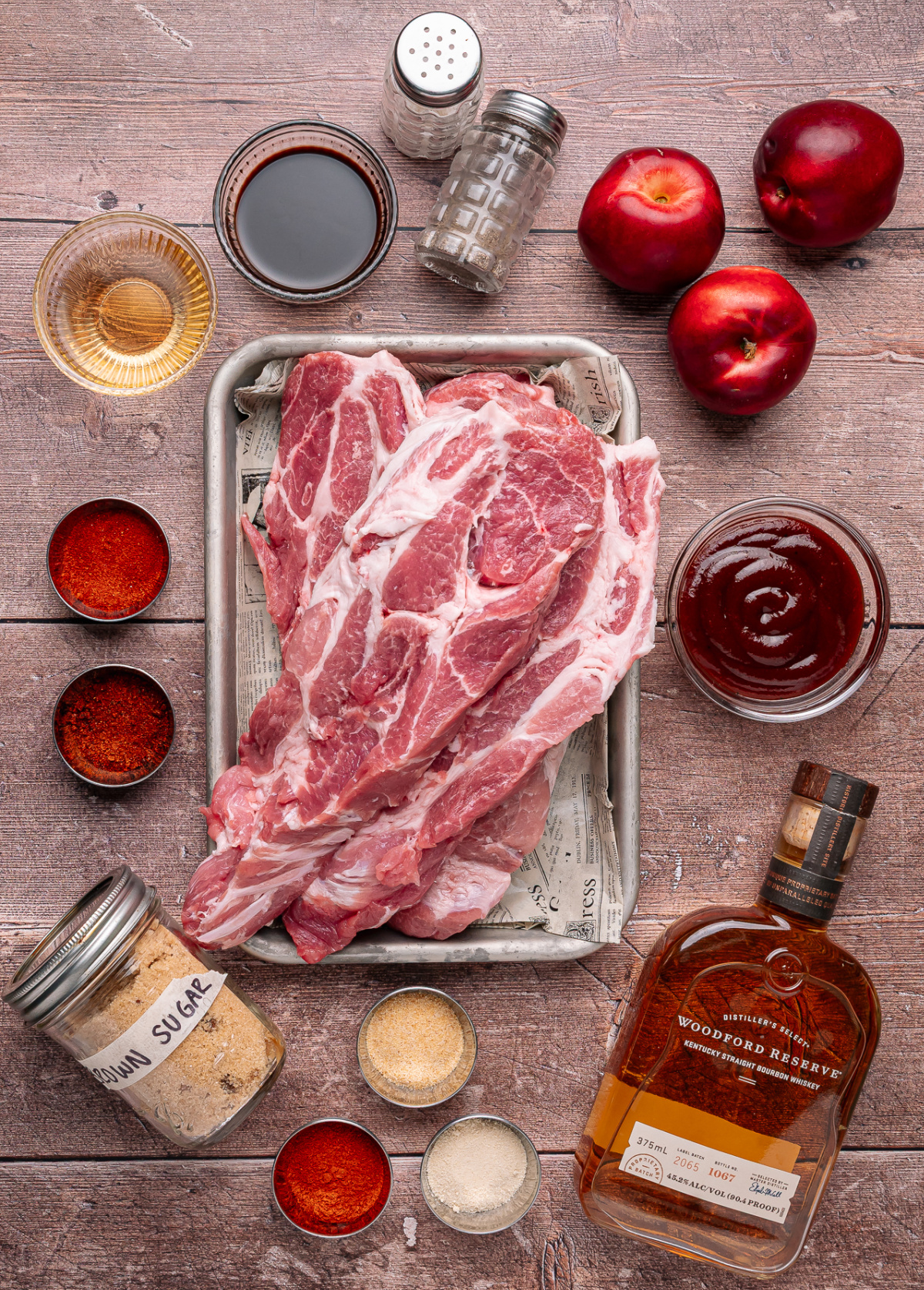 Ingredients for bourbon peach country style ribs including country style pork ribs, fresh peaches, bourbon, barbecue sauce, and spices