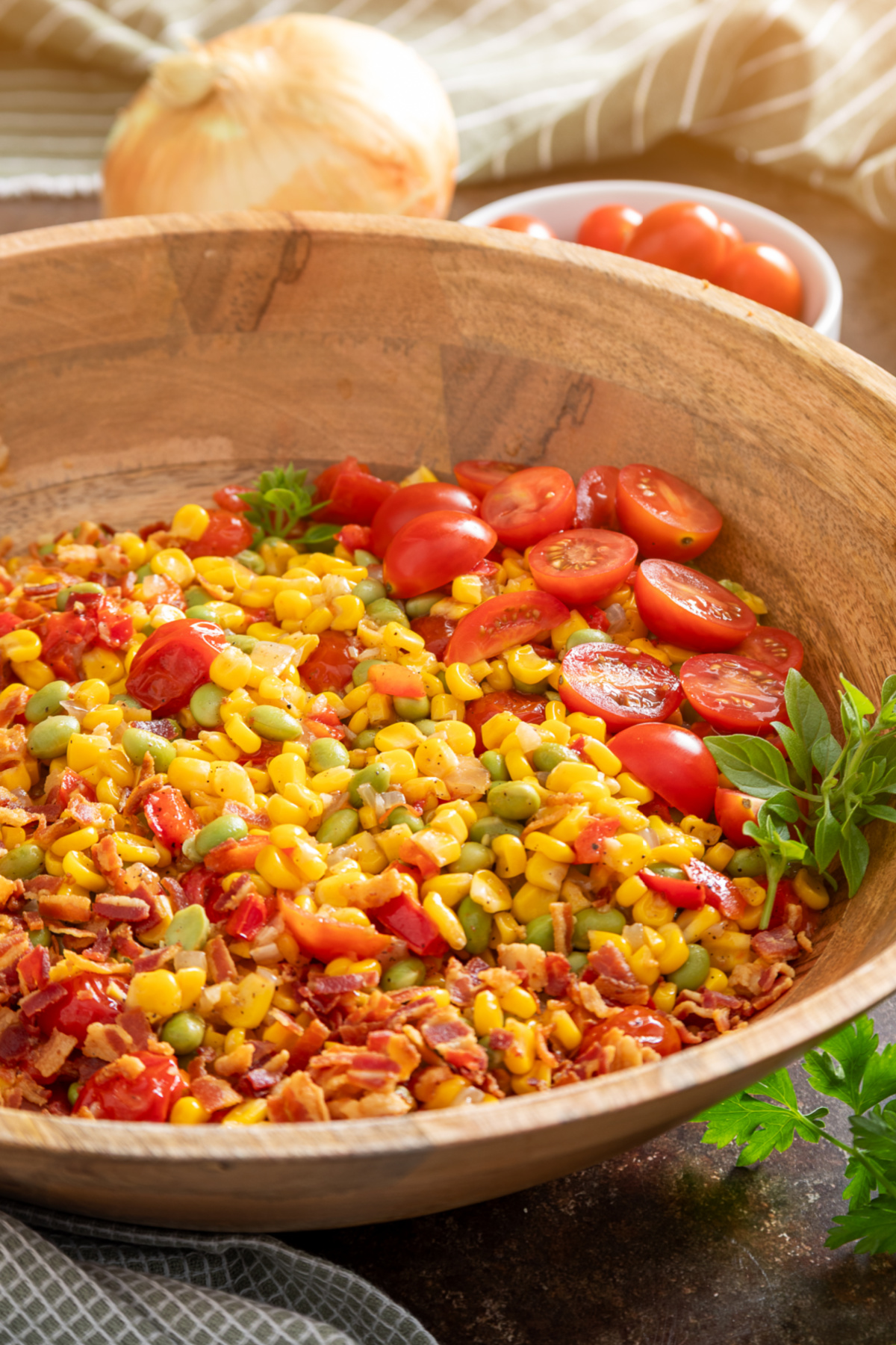 Corn succotash with edamame, bacon, tomatoes, and sweet corn Corn succotash with edamame, bacon, tomatoes, peppers, and sweet corn in a wooden serving bowl