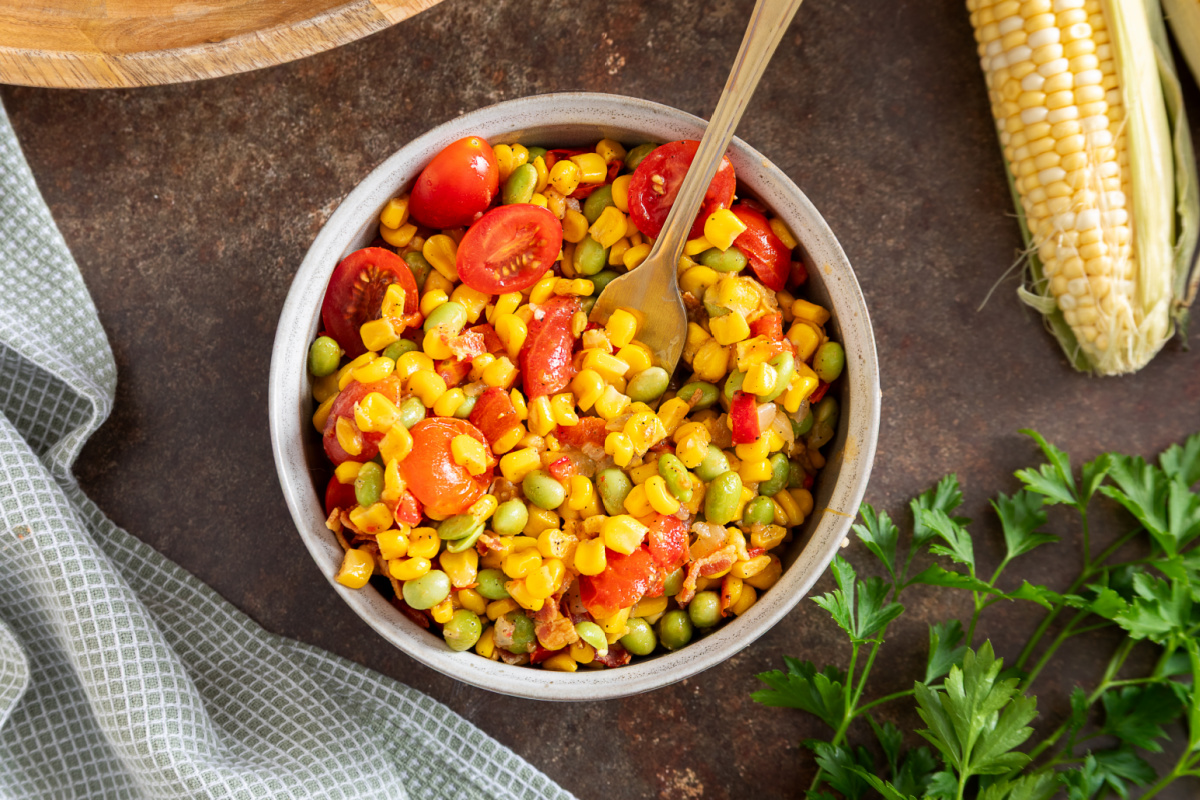 Overhead bowl of succotash with edamame and tomatoes Overhead view of succotash with edamame, sweet corn, tomatoes, and bacon in a serving bowl