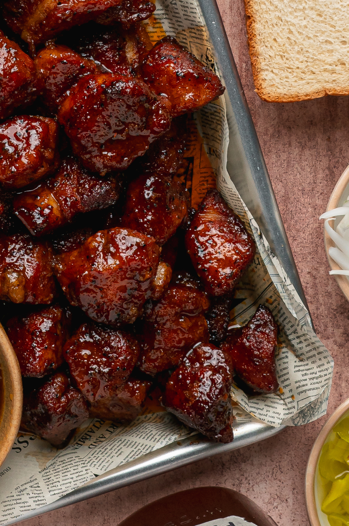 Sticky caramelized pork belly burnt ends with peach tea glaze. Close-up of caramelized pork belly burnt ends coated in a glossy peach tea glaze.