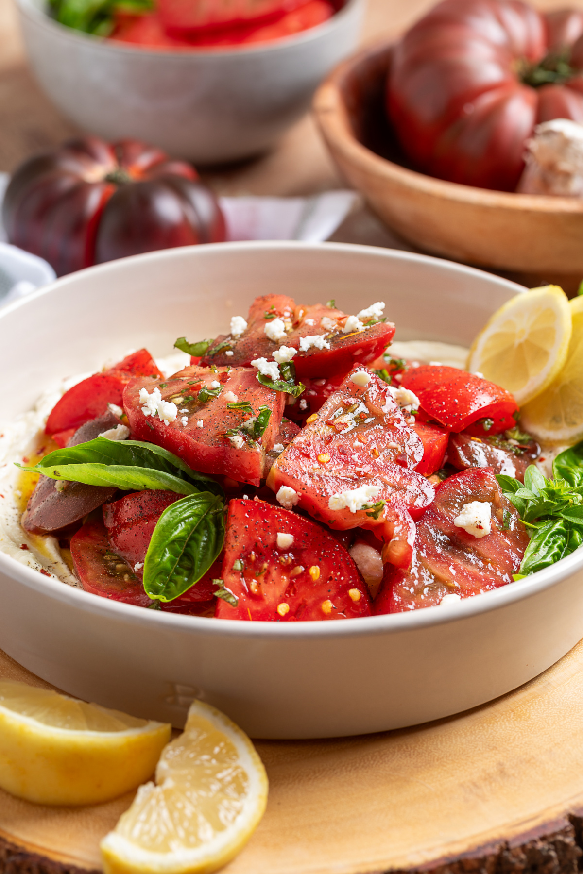 Vertical view of heirloom tomato salad with whipped ricotta feta, fresh basil, and lemon vinaigrette.