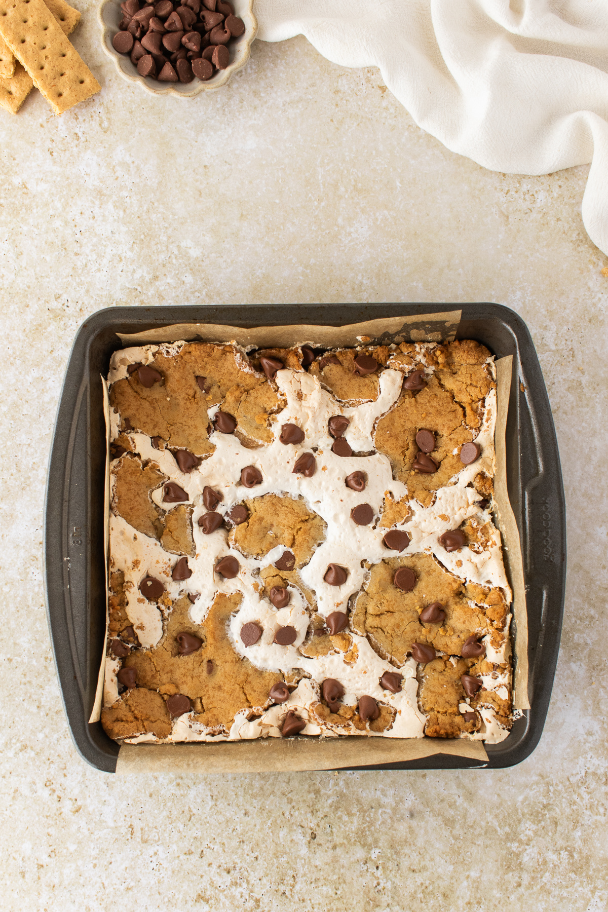 Freshly Baked S'mores Cookie Bars Freshly baked s'mores cookie bars in an 8x8-inch pan with toasted marshmallow and milk chocolate chips.