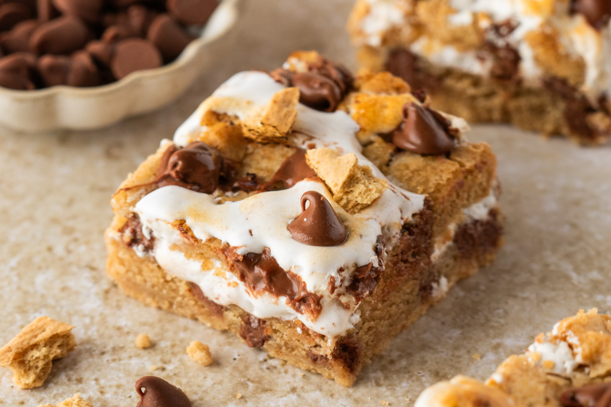 Gooey S'mores Cookie Bars Close-up of s'mores cookie bars with graham cookie dough, toasted marshmallow creme, and milk chocolate.