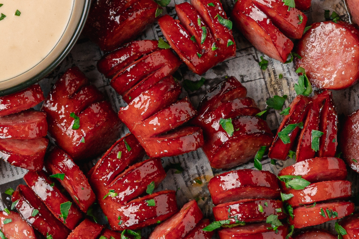 Close-up of sticky honey garlic kielbasa bites with glossy hasselback cuts.