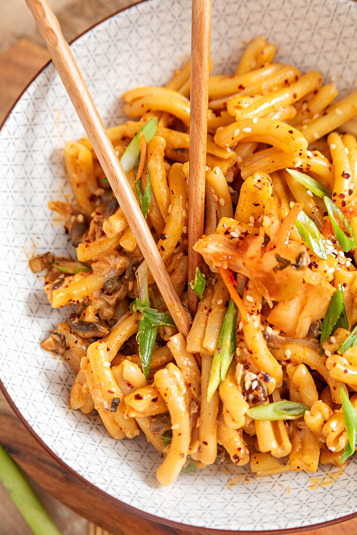 Close-up of creamy gochujang pasta with diced mushrooms, kimchi, green onions and sesame seeds
