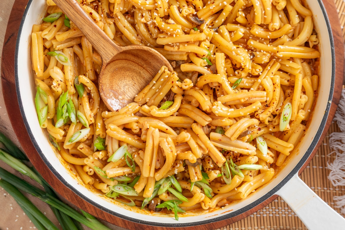 Gochujang pasta with diced mushrooms, green onions, sesame seeds and gochugaru in a skillet