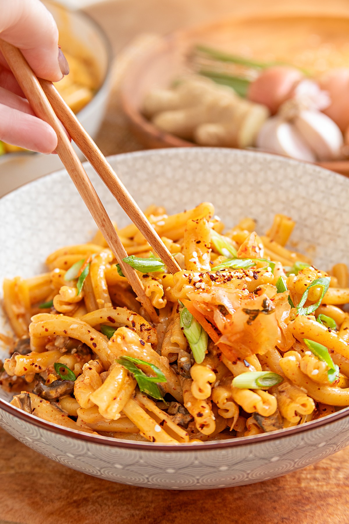 Gochujang pasta with mushrooms, kimchi, green onions and sesame seeds served in a bowl