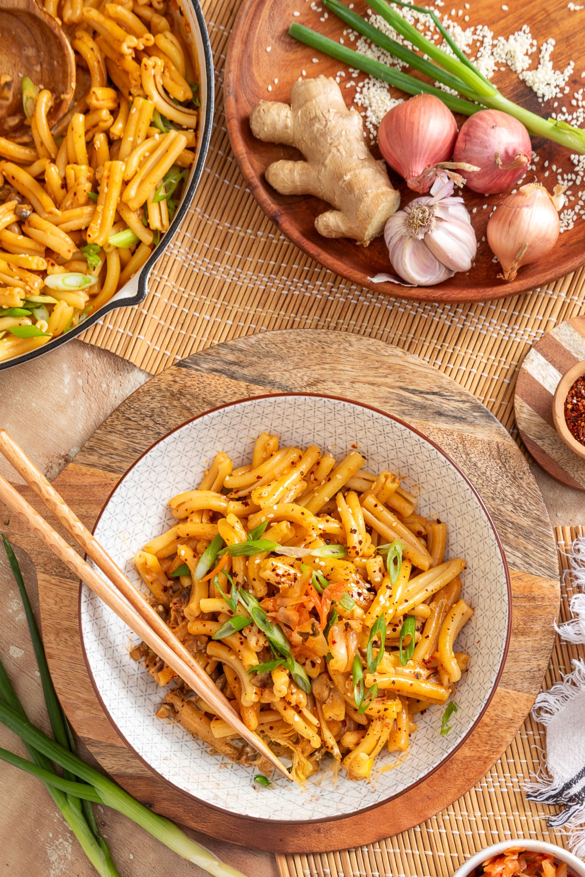 Bowl of gochujang pasta with mushrooms, kimchi, sliced green onions and gochugaru