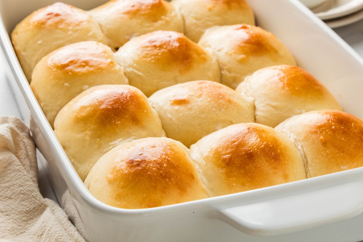 Golden homemade milk bread rolls ready to serve Homemade milk bread rolls with soft pull-apart sides and golden brown tops in a baking dish.