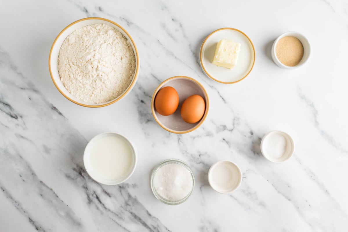 Ingredients for making soft milk bread rolls Ingredients for homemade milk bread rolls including bread flour, whole milk, eggs, butter, sugar, yeast and salt.