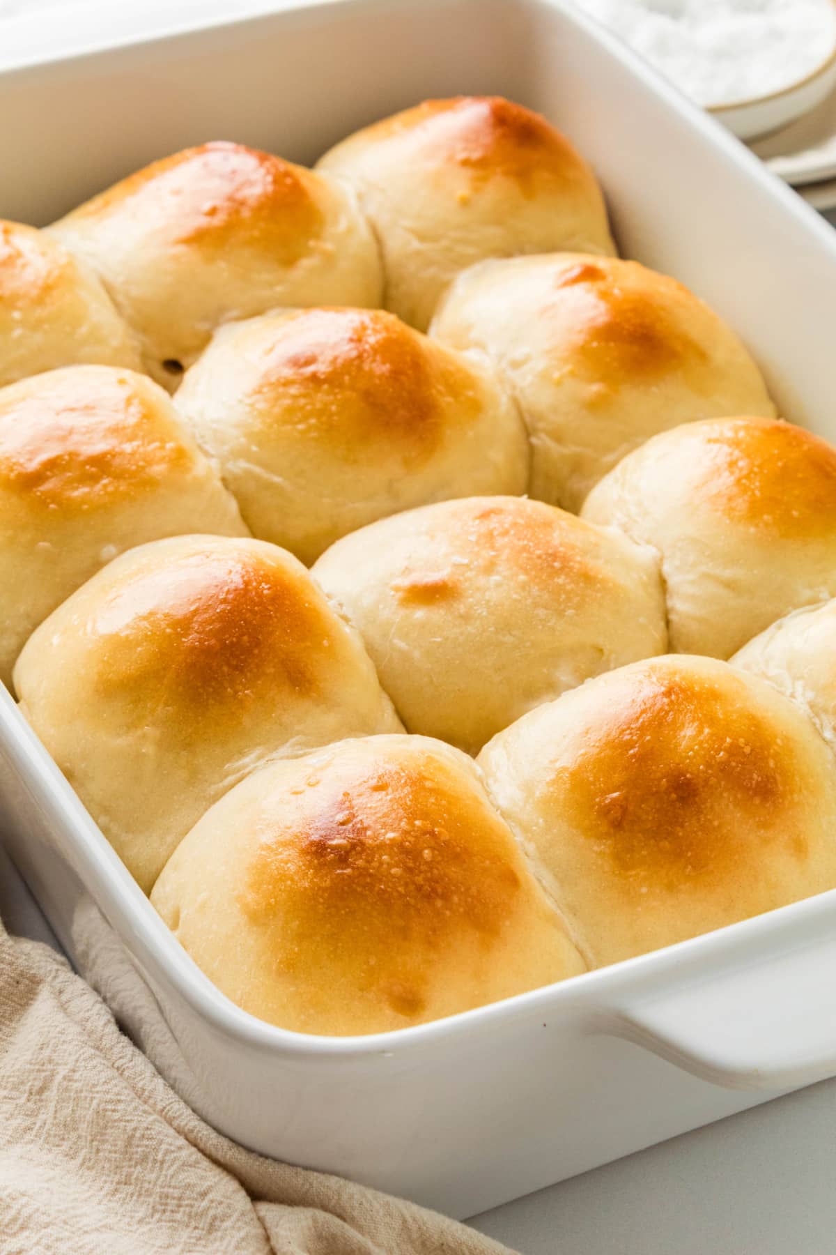 Homemade milk bread rolls baked until golden brown Soft milk bread rolls baked together in a white baking dish with golden brown tops.