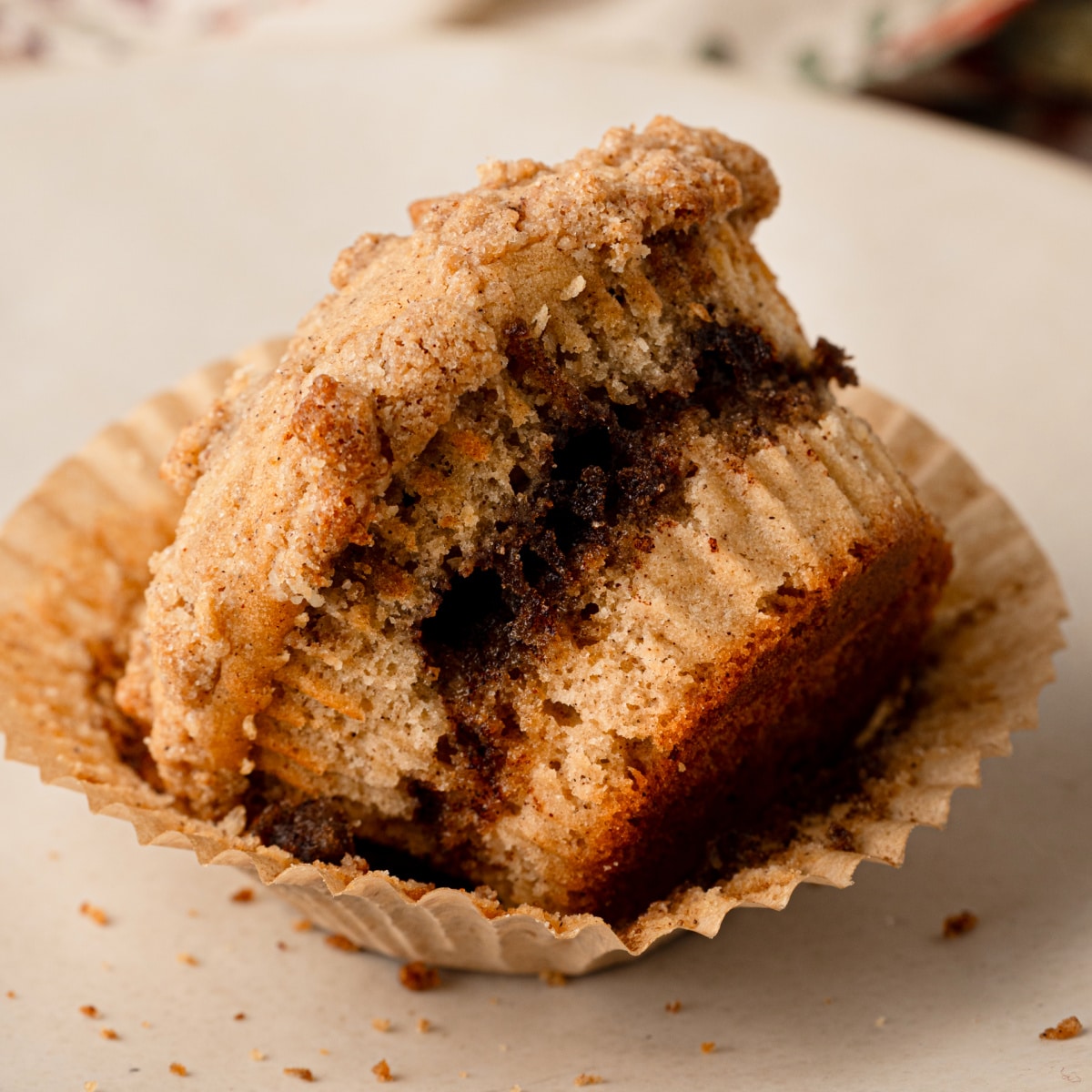Apple cider streusel muffin broken open to show the cinnamon-spiced interior and streusel topping.