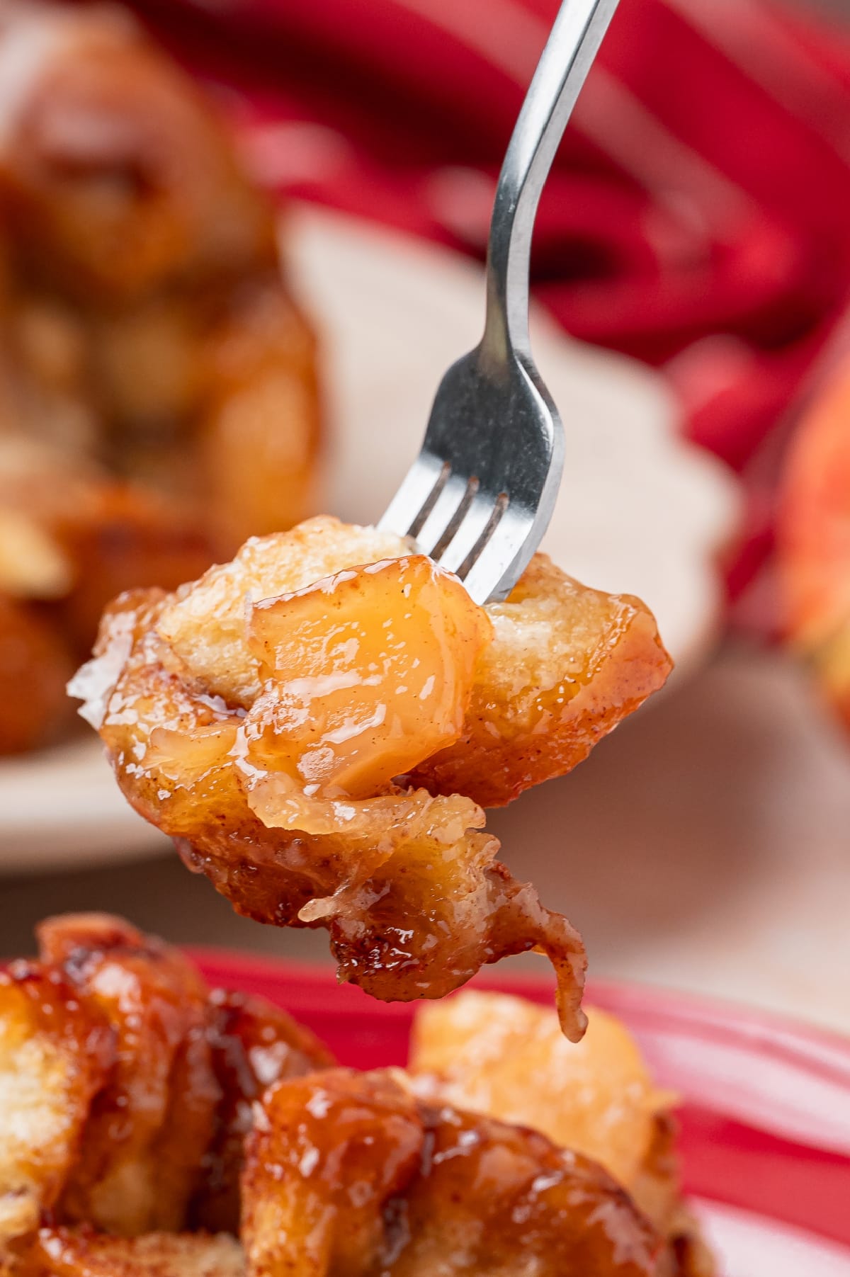 Apple Pie Monkey Bread with Brown Sugar Sauce Forkful of cinnamon roll monkey bread with soft apple pie filling and caramelized brown sugar sauce.