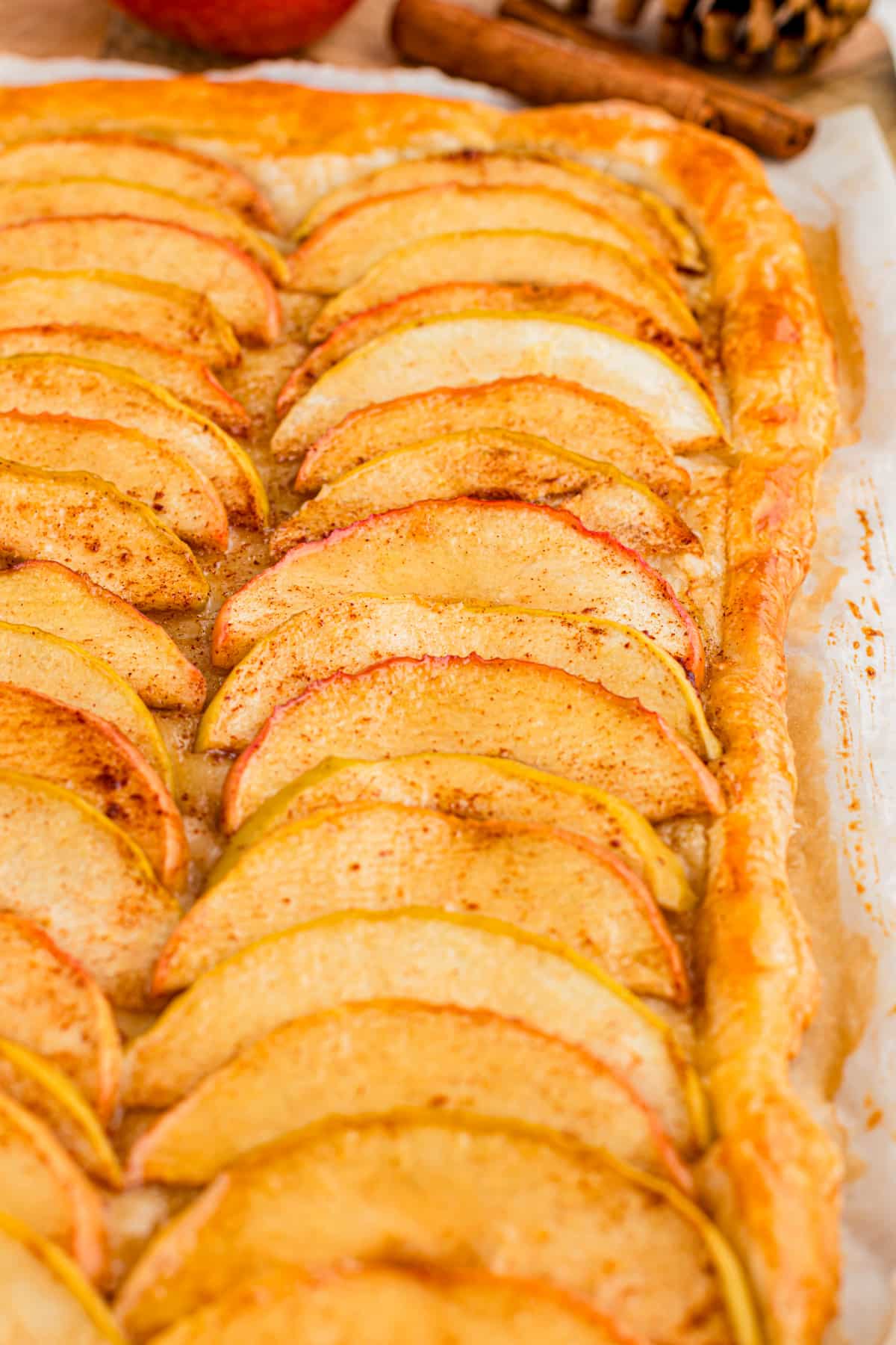 Close-up of overlapping cinnamon apple slices on baked flaky puff pastry