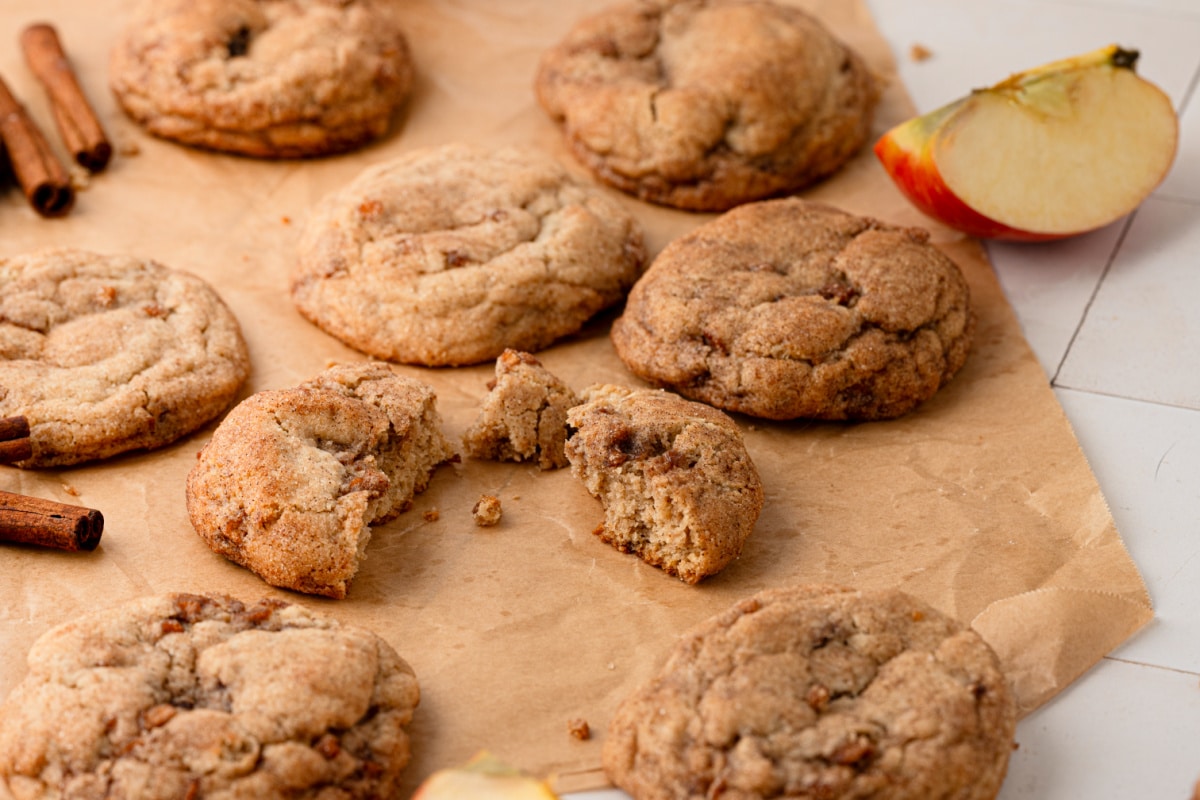 Thick cinnamon sugar cookies with a soft, chewy center and buttery cinnamon-spiced apple throughout. Cinnamon apple cookies broken open to show their soft centers and cooked apple pieces