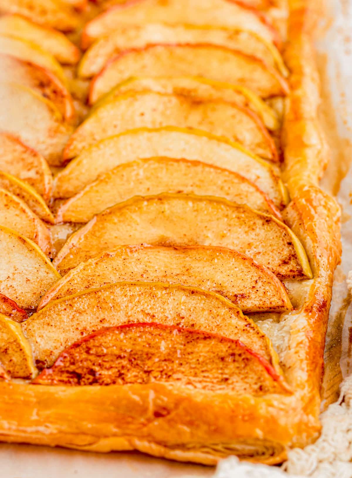 Close-up of thin cinnamon apple slices baked on flaky golden puff pastry