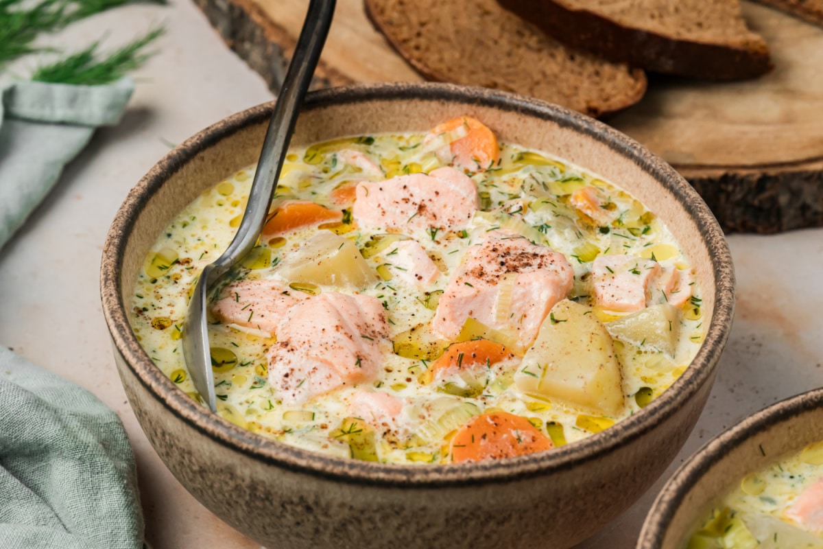 Finnish salmon soup with large pieces of salmon and potatoes in a creamy dill broth. Bowl of Finnish salmon soup with salmon, Yukon Gold potatoes, carrots, leeks and fresh dill in creamy broth.