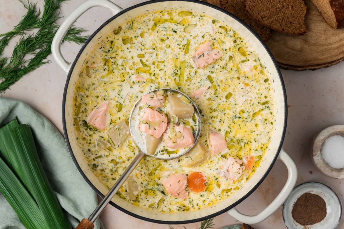 Lohikeitto with salmon and potatoes in a creamy broth with leeks, carrots and fresh dill. Overhead view of Finnish salmon soup with salmon, potatoes, leeks, carrots and dill in a creamy fish broth.
