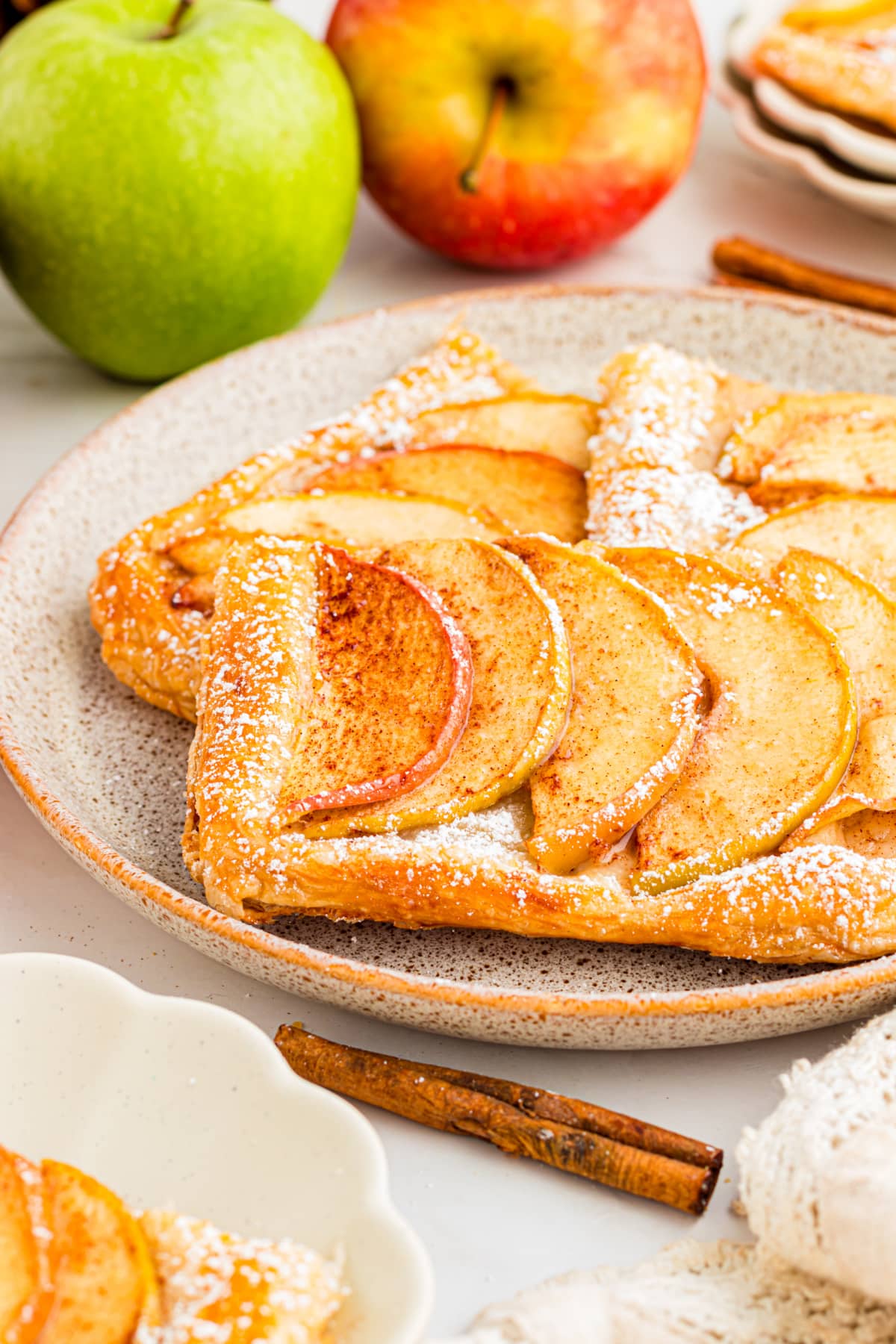 Slice of puff pastry apple tart with cinnamon apples and powdered sugar