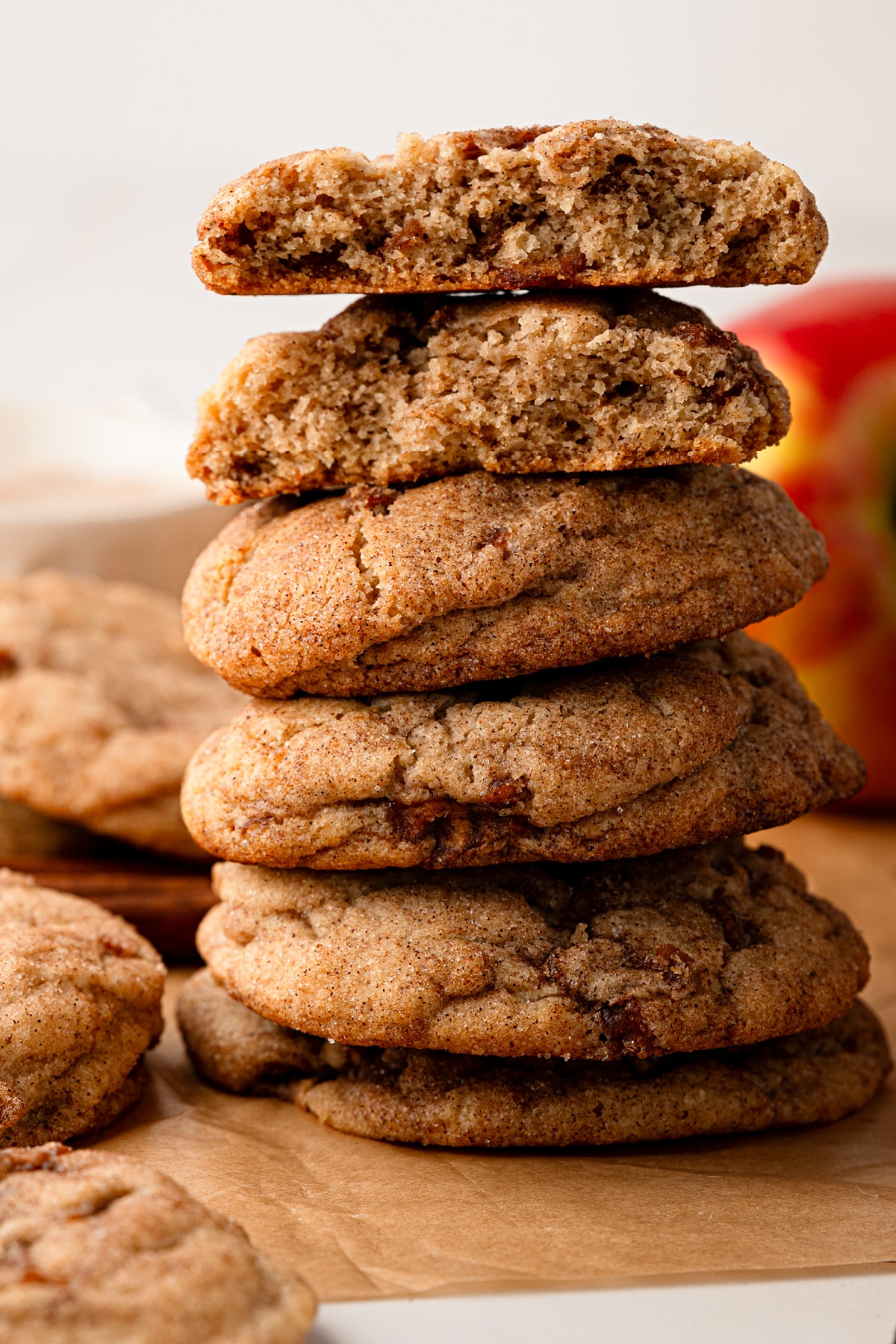 A stack of thick cinnamon sugar cookies showing the soft, chewy interior with buttery cooked apple throughout. Soft cinnamon apple cookies cut open to show the chewy interior and cooked apple pieces