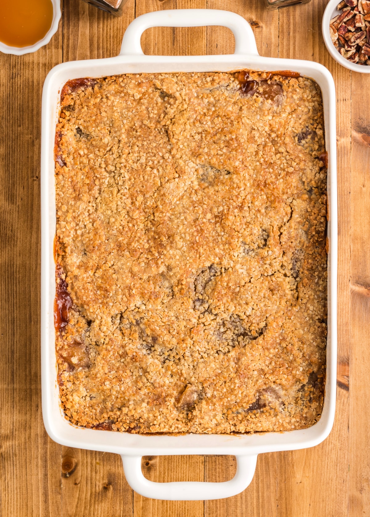 Baked apple crisp dump cake in a white baking dish with a golden, cracked oatmeal cookie topping.