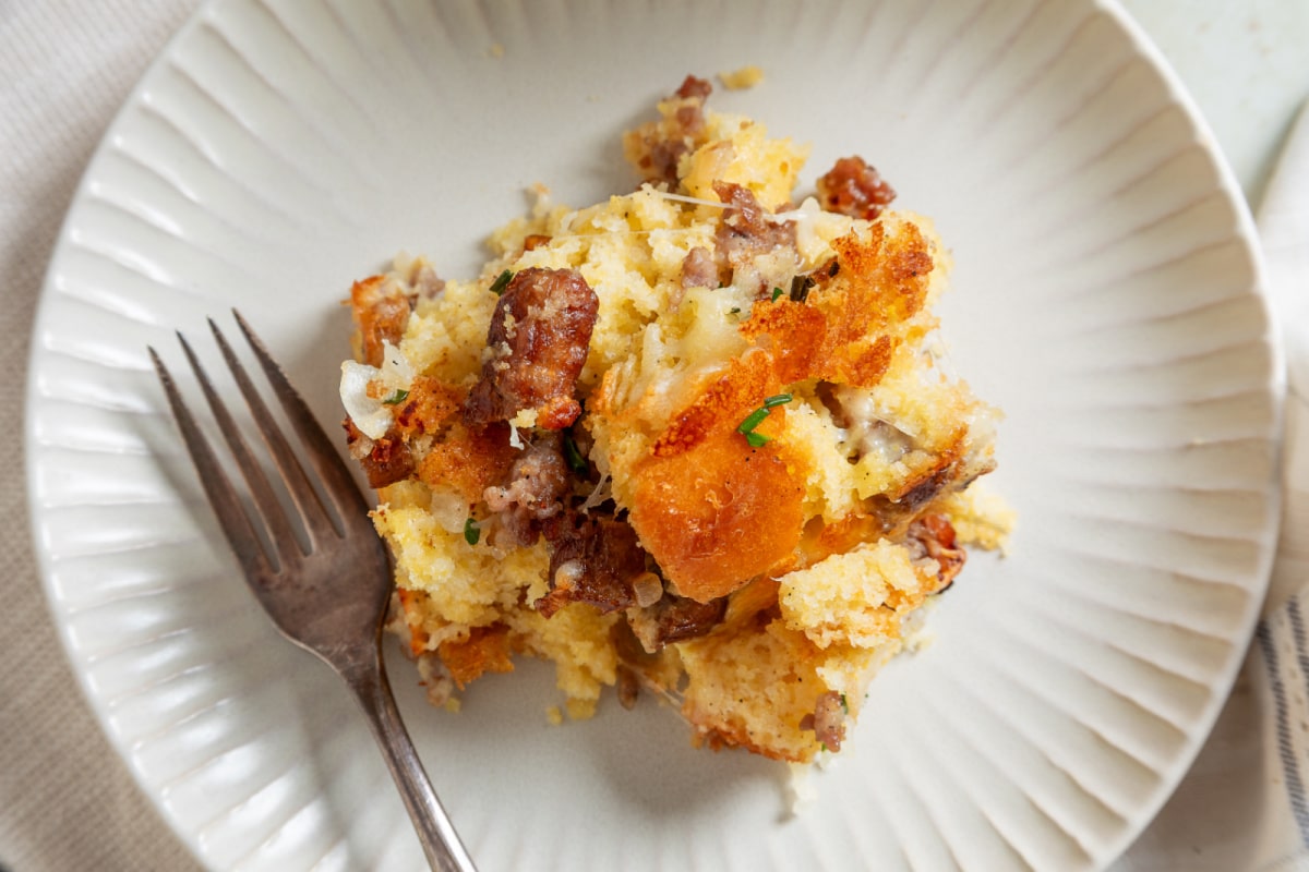 Cornbread breakfast casserole serving with sausage and melted cheese Serving of cornbread breakfast casserole with sausage, melted cheese and browned cornbread