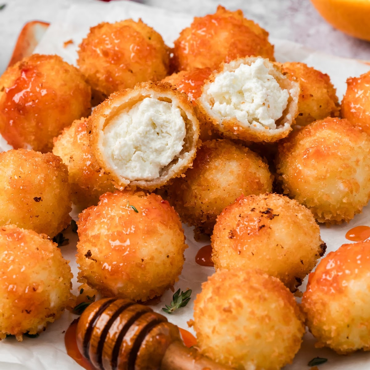 Golden fried goat cheese balls with crunchy panko coating and cranberry hot honey, including two cut-open balls showing the creamy white goat cheese filling.
