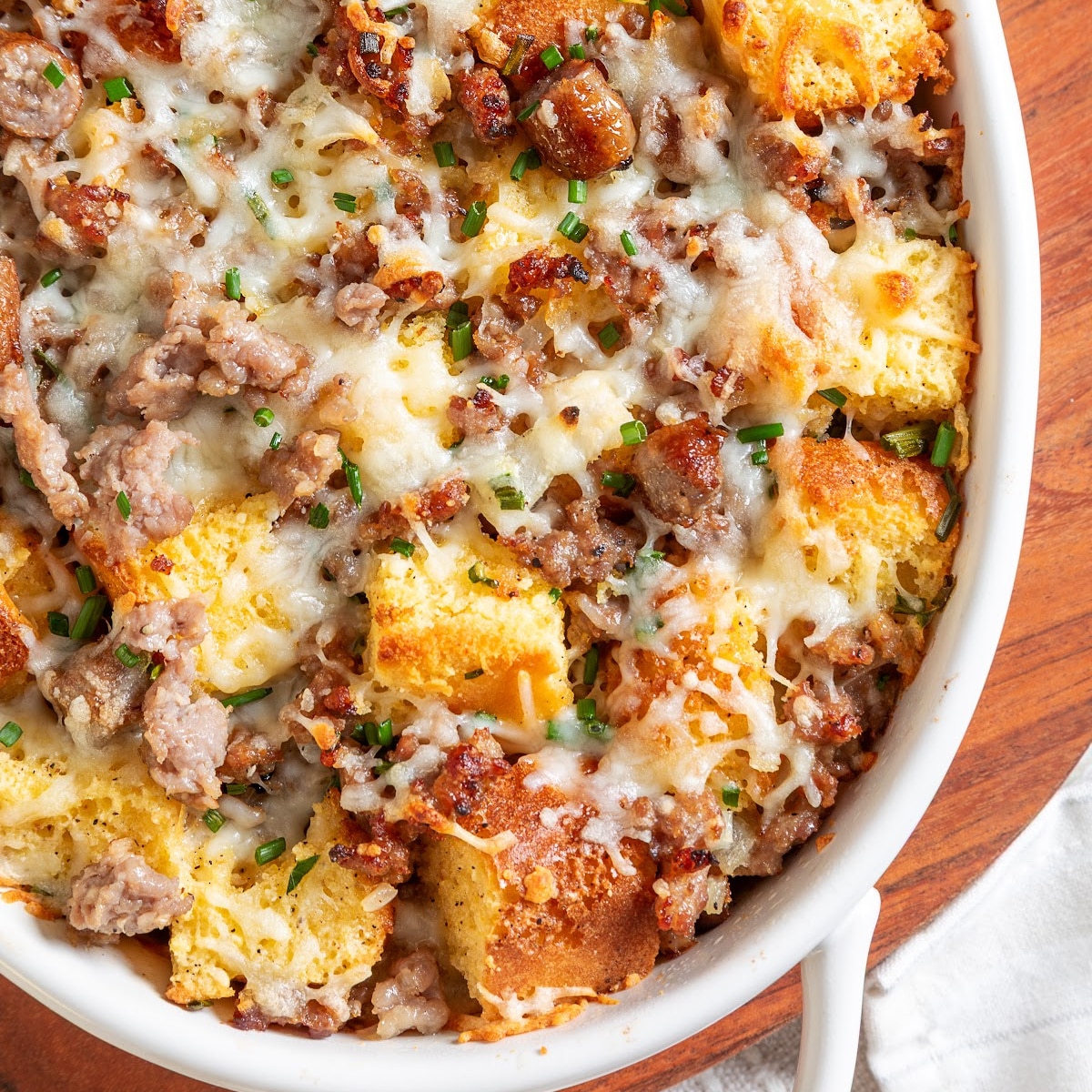 Baked cornbread casserole with browned pieces, sausage and melted cheese Leftover cornbread breakfast casserole with maple sausage, eggs, melted cheese and chives