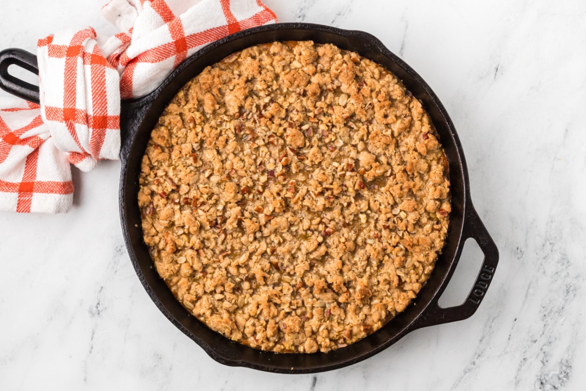 Pumpkin crisp baked in a cast-iron skillet with a golden oat and pecan topping.