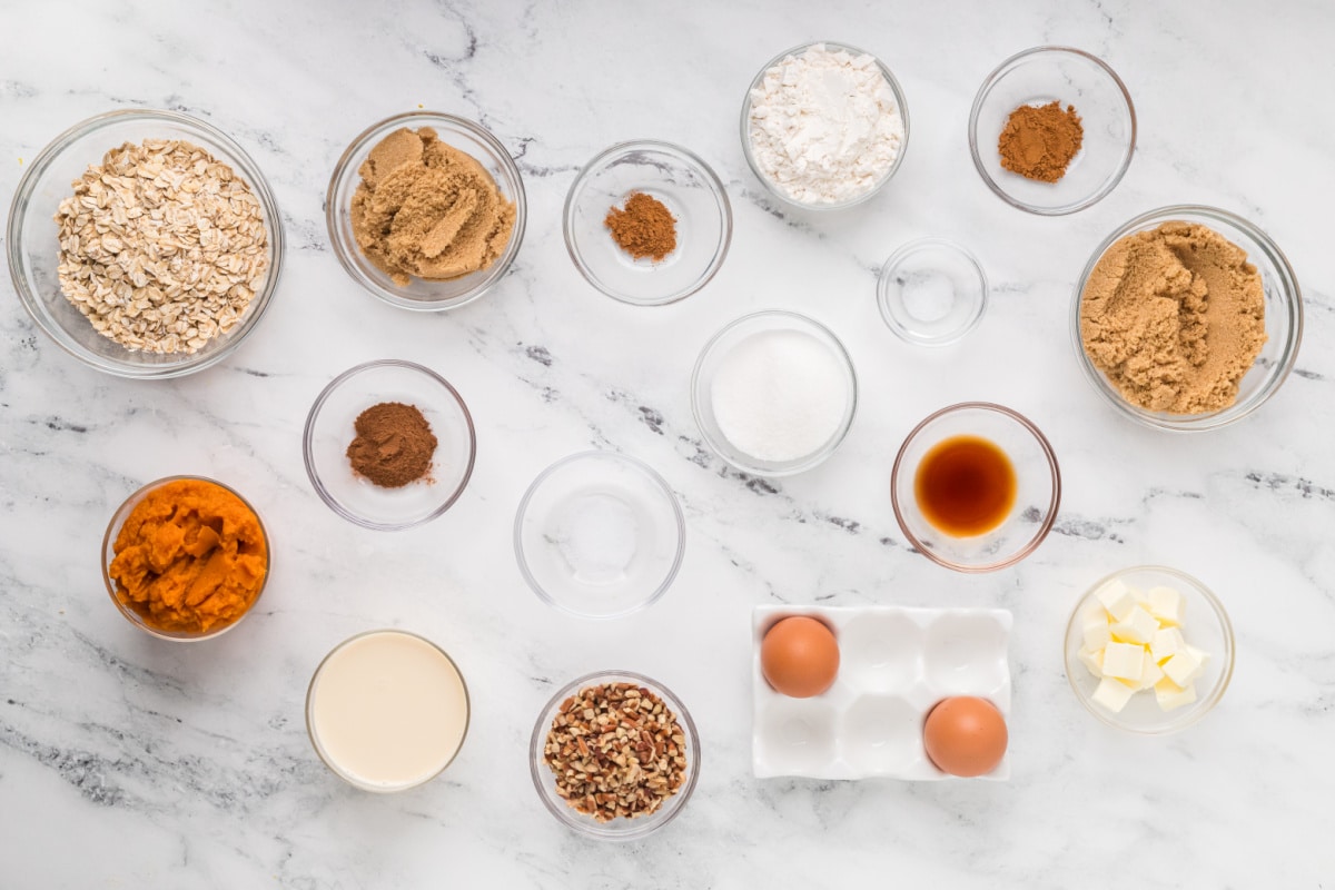 Ingredients for homemade pumpkin crisp, including pumpkin purée, rolled oats, pecans, brown sugar, butter, eggs, evaporated milk, and spices.